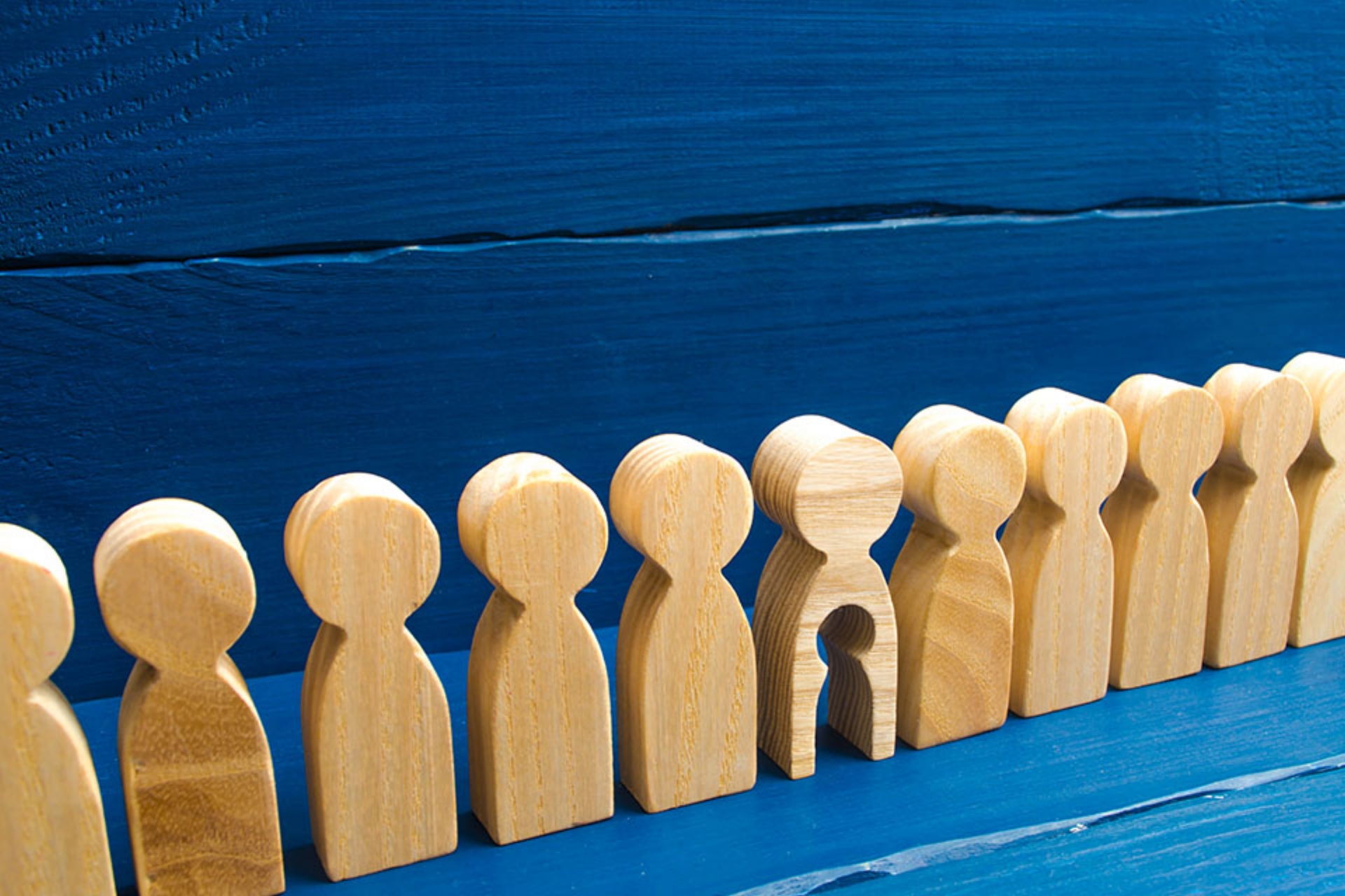 © Andrii Yalanskyi - stock.adobe.com Holzfiguren in einer Reihe, eine hat ein ausgeschnittenes Kind